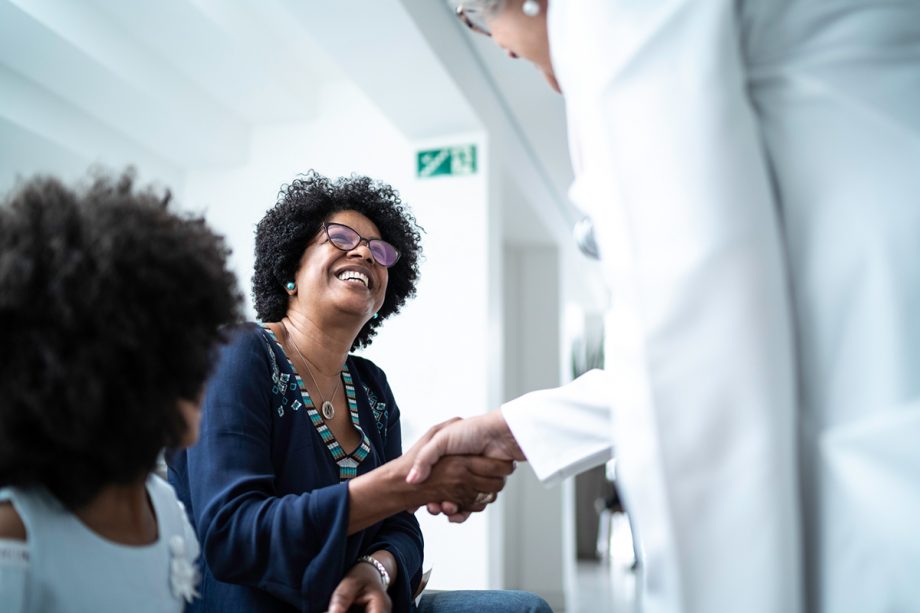 smiling woman shakes doctor's hand