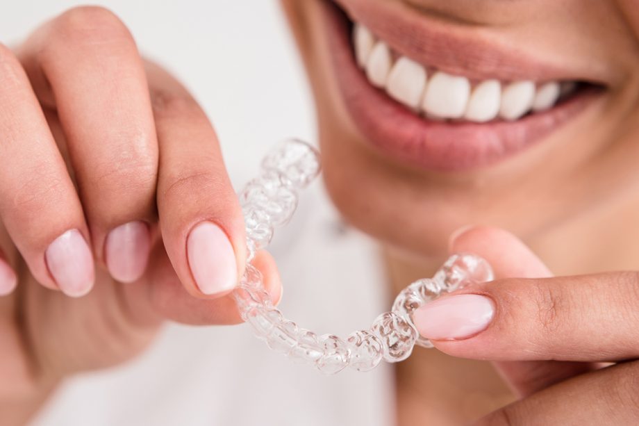 a woman holds an Invisalign aligner